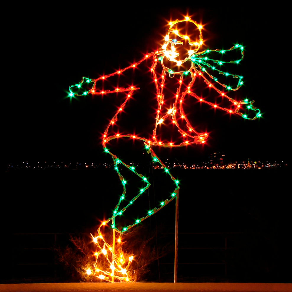 Illuminated holiday display featuring a silhouette of a person in a red winter coat, green scarf, green mittens, and green leggings, created with vibrant red, green, and yellow LED lights. The figure is skating backwards, with bright LED lights creating a dynamic and festive atmosphere against the dark night sky.