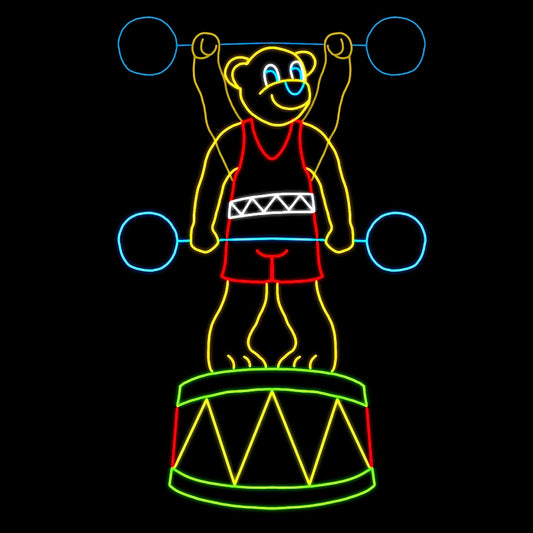 A vibrant LED silhouette display of a teddy bear lifting weights. The animated teddy bear is dressed in a red singlet and stands proudly on a drum. The display features bright colors, with the bear outlined in yellow, the weights in blue, and the drum in green and red. The scene is playful and engaging, making it an eye-catching decoration against a dark background.