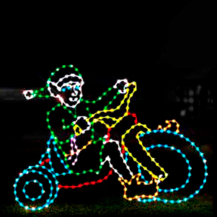 Christmas Elf on Big Wheel Tricycle Silhouette LED Display featuring a scene of a cheerful elf riding a big wheel tricycle. The display is illuminated with bright red, green, blue, yellow, and white LED lights, creating a dynamic and festive scene against a black background. This playful and charming display is perfect for commercial Christmas decorations, ideal for businesses, theme parks, municipalities, and event venues looking to enhance their holiday displays.