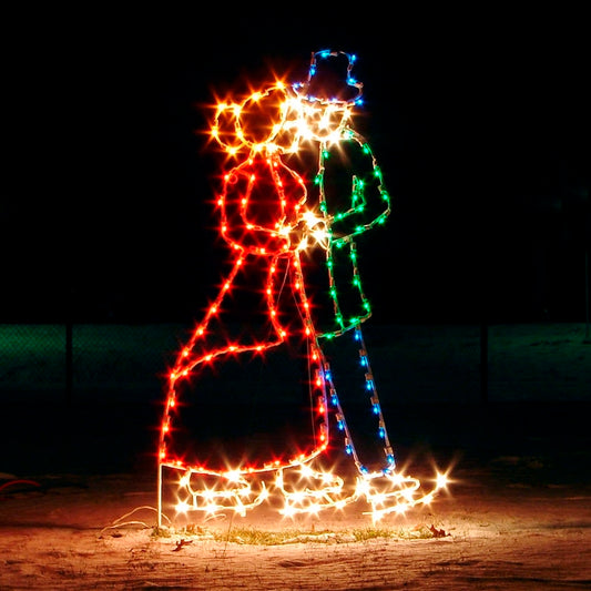 A vibrant silhouette LED display featuring a couple, Victorian dress, ice skating, illuminated in festive colors against a dark night background. The figures are outlined in bright red, green, white, and blue LED lights, creating a charming and romantic Christmas winter scene.