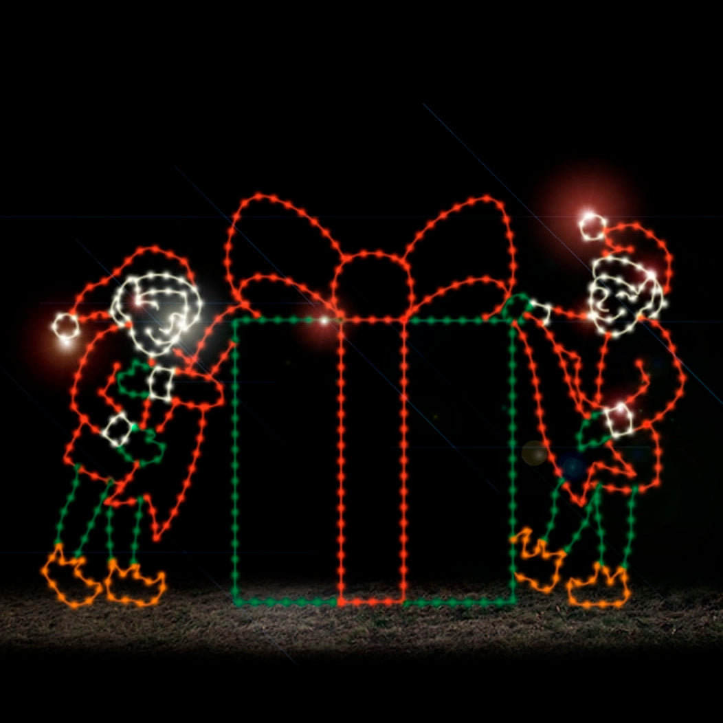 A silhouette LED display of two elves holding a ribbon on a large present, outlined with bright red, green, white, and orange LED lights, set against a dark background.