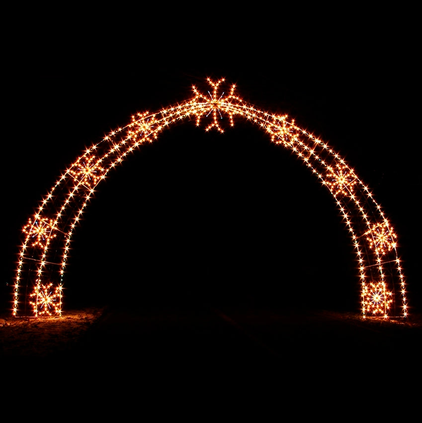 An illuminated, 32 foot by 21 foot archway decorated with snowflake designs made from warm white LED lights, glowing brightly against a dark background. It’s perfect for welcoming visitors and inspiring holiday cheer.